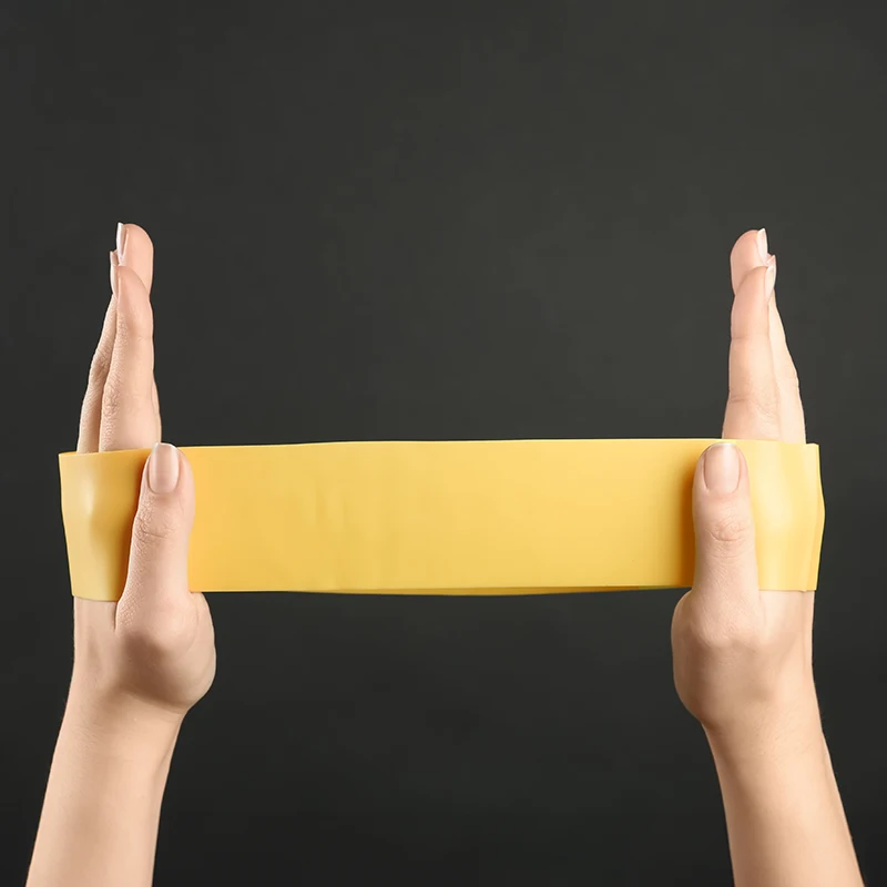 Frau mit Fitnessband vor schwarzem Hintergrund, Nahaufnahme